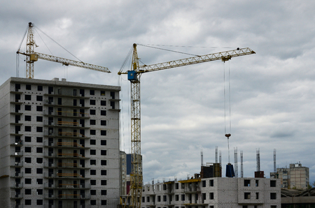 The process of construction. Building materials are delivered to a multi-storey building under construction using a lifting craneのeditorial素材