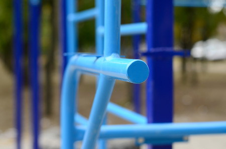 Sports bars in blue on the background of a street sports ground for training in athletics. Outdoor athletic gym equipment. Macro photo with selective focus and extremely blurred backgroundの写真素材