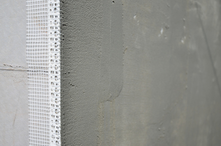 The texture of the wall, covered with gray polystyrene foam plates, which are coated with a reinforcing mixture with a plastic reinforcing profile corner. Stage of wall insulationの写真素材