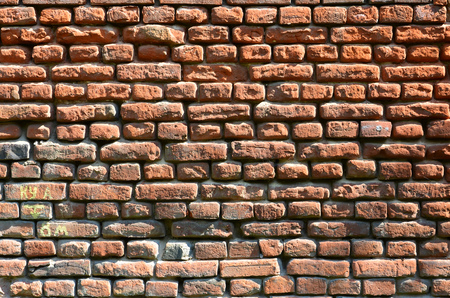 Horizontal wall texture of several rows of very old brickwork made of red brick. Shattered and damaged brick wall with pinched cornersの写真素材