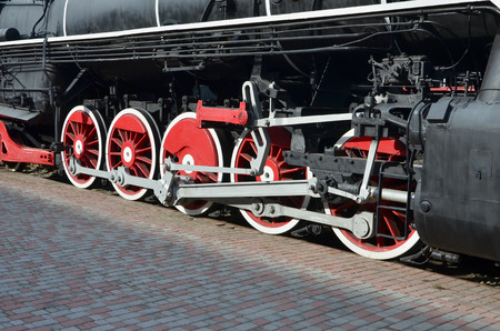 Wheels of the old black steam locomotive of Soviet times. The side of the locomotive with elements of the rotating technology of old trainsの写真素材