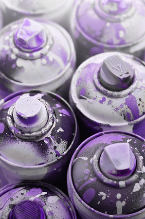 A lot of used spray cans of paint close-up. Dirty and smeared cans for drawing graffiti. The concept of a sweeping and careless drawing of paint. Creative art imageの写真素材