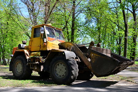 The city improvement team removes the fallen leaves in the park with an excavator and a truck. Regular seasonal work on improving the public places for recreationの写真素材