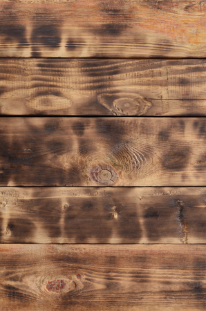 The texture of the scorched wooden wall. Wall of smooth orange long wooden boards with a specific black texture of fryingの写真素材