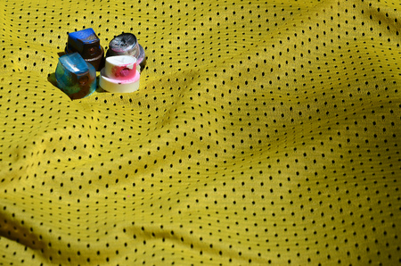 Several caps for used aerosol paint sprayers lie on the sports shirt of a basketball player made of polyester fabric. The concept of youth street art, active sports and eventful lifestyleの写真素材