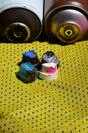 Several caps for used aerosol paint sprayers lie on the sports shirt of a basketball player made of polyester fabric. The concept of youth street art, active sports and eventful lifestyleの写真素材