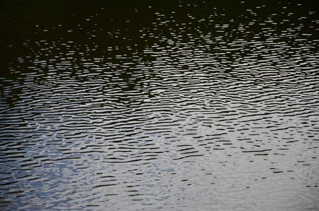 The texture of dark river water under the influence of wind, imprinted in perspective. Horizontal imageの写真素材