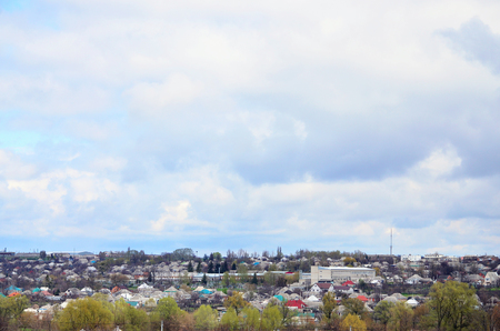 A rural landscape with many private houses and green trees. Suburban panorama on a cloudy afternoon. A place far from the cityの写真素材