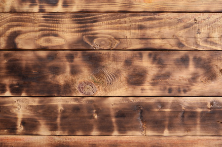 The texture of the scorched wooden wall. Wall of smooth orange long wooden boards with a specific black texture of fryingの写真素材