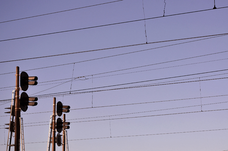 Railroad traffic light against clear blue sky, Contact wire. High voltage railroad power lines on neutral blue sky background with traffic lightsの写真素材