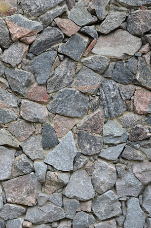 The texture of a strong stone wall of many concreted stones of various shapesの写真素材