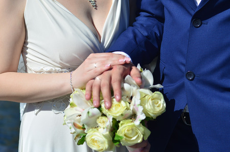 The newlywed couple is holding a beautiful wedding bouquet. Classical wedding photography, symbolizing unity, love and the creation of a new familyの写真素材