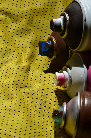 Several used aerosol paint sprayers lie on the sports shirt of a basketball player made of polyester fabric. The concept of youth street art, active sports and eventful lifestyleの写真素材