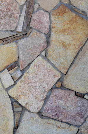 The texture of a strong stone wall of many concreted stones of various shapesの写真素材