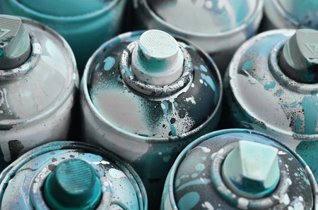 A lot of used spray cans of paint close-up. Dirty and smeared cans for drawing graffiti. The concept of a sweeping and careless drawing of paint. Creative art imageの写真素材