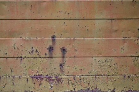 Texture of an old orange metal wall with significant damage from exposure to unfavorable weather conditions and dampnessの写真素材