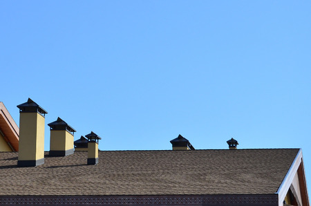 Modern roofing and decoration of chimneys. Flexible bitumen or slate shingles. The absence of...