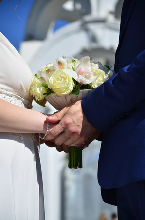 The newlywed couple is holding a beautiful wedding bouquet. Classical wedding photography, symbolizing unity, love and the creation of a new familyの写真素材