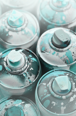 A lot of used spray cans of paint close-up. Dirty and smeared cans for drawing graffiti. The concept of a sweeping and careless drawing of paint. Creative art imageの写真素材
