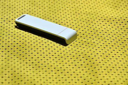 A modern portable USB internet adapter is placed on the yellow sportswear made of polyester nylon fiberの写真素材