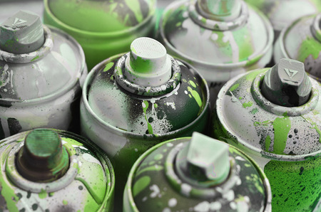 A lot of used spray cans of paint close-up. Dirty and smeared cans for drawing graffiti. The concept of a sweeping and careless drawing of paint. Creative art imageの写真素材