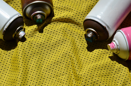 Several used aerosol paint sprayers lie on the sports shirt of a basketball player made of polyester fabric. The concept of youth street art, active sports and eventful lifestyleの写真素材