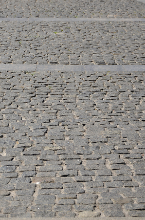 The texture of the paving slab (paving stones) of many small stones of a square shape under bright sunlightの写真素材