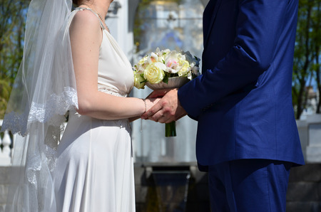 The newlywed couple is holding a beautiful wedding bouquet. Classical wedding photography, symbolizing unity, love and the creation of a new familyの写真素材