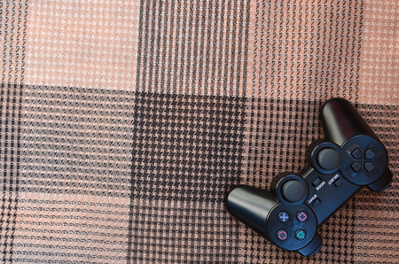 The video game controller from the game console is on the checkered sofa. Wireless device for...