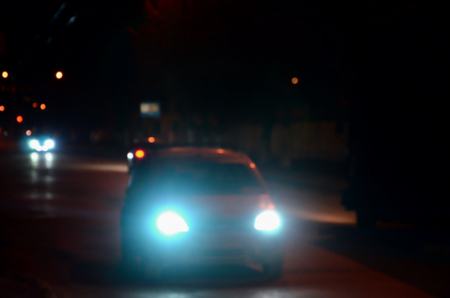 Nights lights of the big city, the blurred night avenue with bokeh traffic lights and headlights of the approaching carsの写真素材