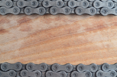 Dirty and oily chain from a mountain bike lying on a wooden table in a bicycle shop. One of the main elements of the transmission of torque on bikes and bicycles close upの写真素材