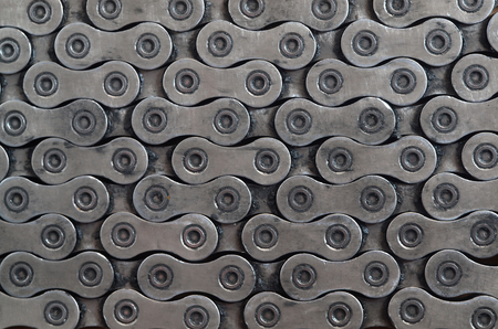 Dirty and oily chain from a mountain bike lying on a wooden table in a bicycle shop. One of the main elements of the transmission of torque on bikes and bicycles close upの写真素材