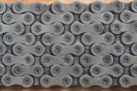 Dirty and oily chain from a mountain bike lying on a wooden table in a bicycle shop. One of the main elements of the transmission of torque on bikes and bicycles close upの写真素材