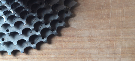 Background image of a rear cassette from a mountain bike lying on a wooden table in a bike shop. One of the main components for switching speeds on sport bikes and mountain bikesの写真素材