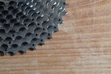 Background image of a rear cassette from a mountain bike lying on a wooden table in a bike shop. One of the main components for switching speeds on sport bikes and mountain bikesの写真素材