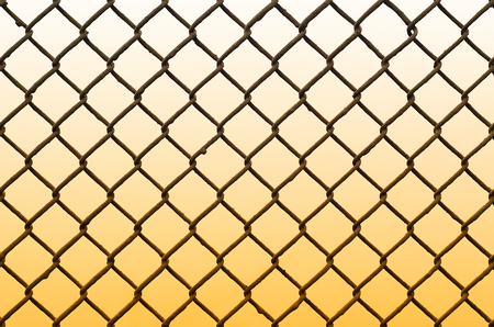 Texture of an old and rusty metal mesh on a neutral colored background. A sad and gloomy image with a flat fencing net used in prisons or industrial plantsの写真素材
