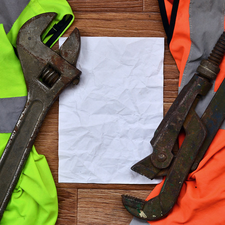 Adjustable wrenches and paper lies of an orange and green signal worker shirts. Still life associated with repair, railway or plumbing worksの写真素材