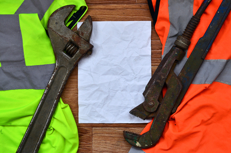 Adjustable wrenches and paper lies of an orange and green signal worker shirts. Still life associated with repair, railway or plumbing worksの写真素材