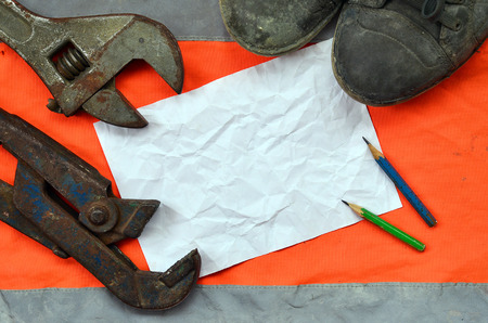 Adjustable wrenches with old boots and a sheet of paper with two pencils. Still life associated with repair, railway or plumbing worksの写真素材