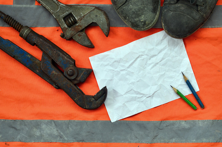 Adjustable wrenches with old boots and a sheet of paper with two pencils. Still life associated with repair, railway or plumbing worksの写真素材