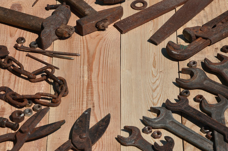 A set of old and rusty tools for handyman. A lot of obsolete household tools from rusty metal lie on a wooden table in the workshop. The concept of home repair and construction worksの写真素材