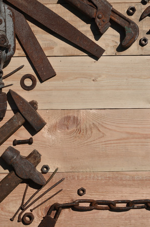 A set of old and rusty tools for handyman. A lot of obsolete household tools from rusty metal lie on a wooden table in the workshop. The concept of home repair and construction worksの写真素材
