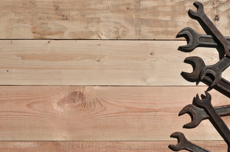 A few rusty spanners on a wooden background. Obsolete household tools made of rusty metal lie on a wooden table in a workshop. The concept of repair and construction worksの写真素材