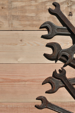 A few rusty spanners on a wooden background. Obsolete household tools made of rusty metal lie on a wooden table in a workshop. The concept of repair and construction worksの写真素材
