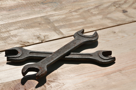 A few rusty spanners on a wooden background. Obsolete household tools made of rusty metal lie on a wooden table in a workshop. The concept of repair and construction worksの写真素材