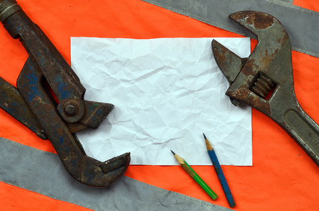 Adjustable wrenches and a sheet of paper with two pencils. Still life associated with repair, railway or plumbing worksの写真素材