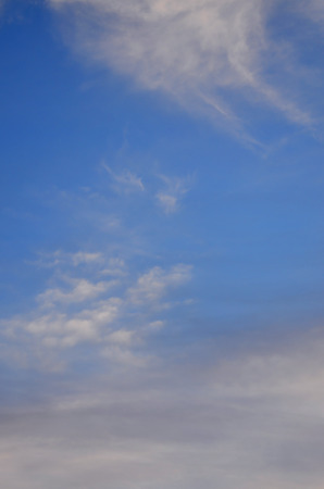 A photo of a bright and shiny blue sky with fluffy and dense white clouds of different sizes and shapes. Beautiful sky on a clear spring afternoonの写真素材