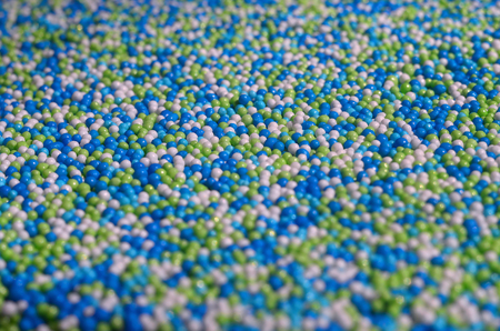 Background picture of a variety of colored glazed powder in the form of small balls. A huge number of sweet, colorful beads of very small size for decoration of pastry productsの写真素材