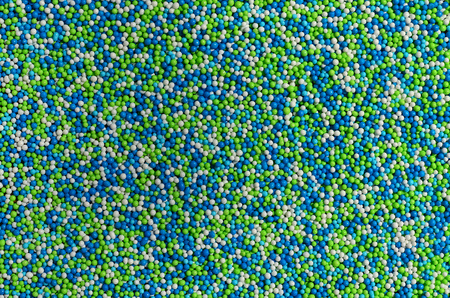 Background picture of a variety of colored glazed powder in the form of small balls. A huge number of sweet, colorful beads of very small size for decoration of pastry productsの写真素材