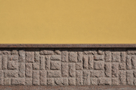The horizontal texture of the foundation in the form of a mosaic made of a dark, coarse and strong granite stone in the sunlight outdoorsの写真素材